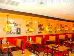 Shot of the main room at Lula Ray's diner, featuring bright yellow walls with red trim, hanging yellow lamps over each booth. The walls are covered in old photographs and art pieces, too pixilated to identify. Never let the lights go out.